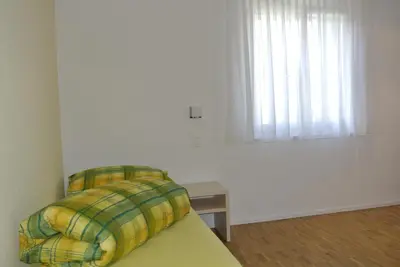 a white bedroom with a bed and a window at Hotel Garni Bären Bazenheid in Bazenheid