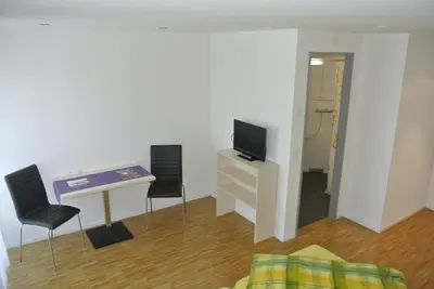 a living room with a tv and a table and chairs at Hotel Garni Bären Bazenheid in Bazenheid