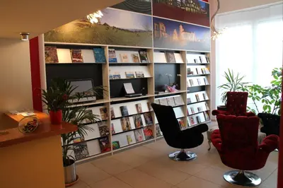 a library with two chairs and a book shelf with books at Boutique City Hotel Gallo in St. Gallen