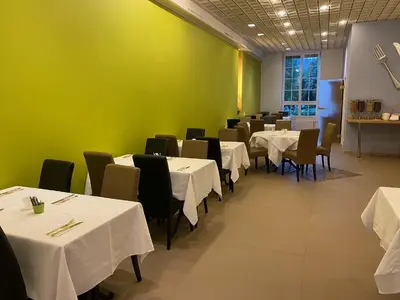 a dining room with tables and chairs and a green wall at Boutique City Hotel Gallo in St. Gallen