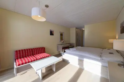 a bedroom with a bed and a red couch at Hotel Säntis Lodge in Unterwasser