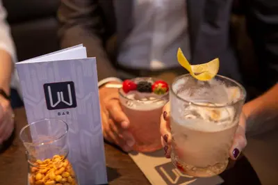 a person holding two drinks on a table at Hotel Walhalla in St. Gallen