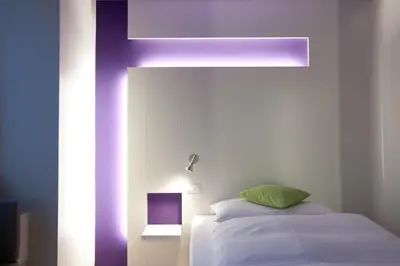 a bedroom with a bed and a purple beam at Hotel Dom, zentral - herzlich - sozial engagiert in St. Gallen