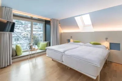 a bedroom with a large white bed and a large window at Hotel Dom, zentral - herzlich - sozial engagiert in St. Gallen