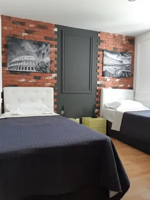 a bedroom with two beds and a brick wall at Rome Apartment in Rheineck
