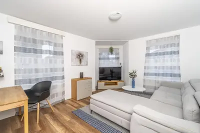 a white living room with a couch and a table at Aparthotel Mama Home Arbon in Arbon