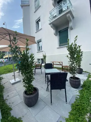 a patio with a table and chairs and trees at Aparthotel Mama Home Arbon in Arbon