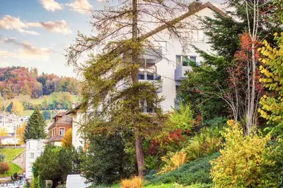 a building on a hill with trees and bushes at VISIMO Apartments Lehnstrasse St Gallen - Stylish, Smart, Connected in St. Gallen