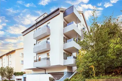 an apartment building with white balconies and trees at VISIMO Apartments Lehnstrasse St Gallen - Stylish, Smart, Connected in St. Gallen