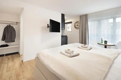 a white bedroom with two towels on a bed at VISIMO Apartments Lehnstrasse St Gallen - Stylish, Smart, Connected in St. Gallen