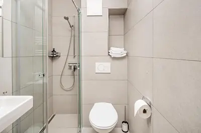 a bathroom with a toilet and a glass shower at VISIMO Apartments Lehnstrasse St Gallen - Stylish, Smart, Connected in St. Gallen