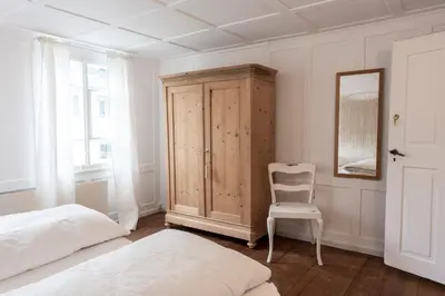 a bedroom with a bed and a cabinet and a chair at Villa Donkey Ferienwohnung 113 in Degersheim
