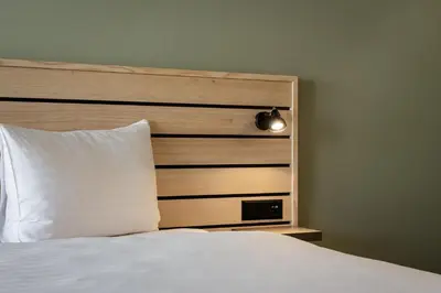 a bedroom with a white bed with a wooden headboard at flexymotel Buchs in Buchs