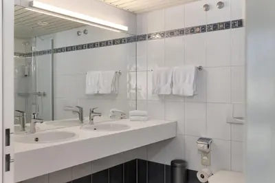 a white bathroom with two sinks and a mirror at flexymotel Buchs in Buchs