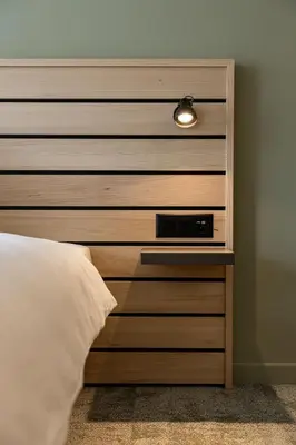 a wooden headboard with a clock in a bedroom at flexymotel Buchs in Buchs