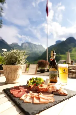 a plate of food on a table with a bottle of beer at Hotel Frohe Aussicht in Weissbad