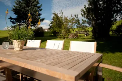 a wooden table with white chairs in a yard at Hotel Frohe Aussicht in Weissbad