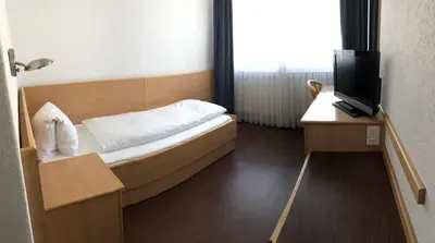 a small bedroom with a bed and a tv at Hotel Metropol in Widnau