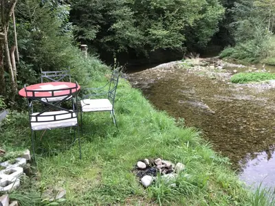 a table and chairs sitting next to a river at Appenzellerland - Ferienhaus 