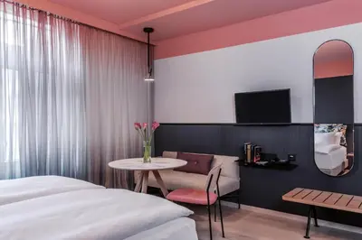 a bedroom with a bed and a table and a chair at Sorell Boutique-Hotel City Weissenstein St Gallen in St. Gallen