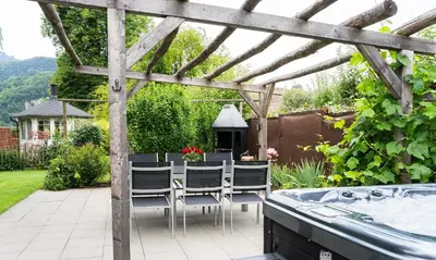 a patio with a table and chairs under a wooden pergola at Ferienhaus Kluser in Oberriet