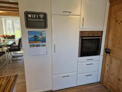a kitchen with a white refrigerator and a sign on a wall at Ferienhaus Kluser in Oberriet