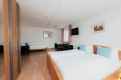 a bedroom with a bed and a desk in a room at Hotel Krone Gais in Gais