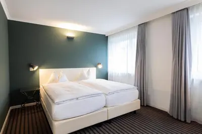 a bedroom with a large white bed and a window at Self Check-In Hotel David 22 in St. Gallen