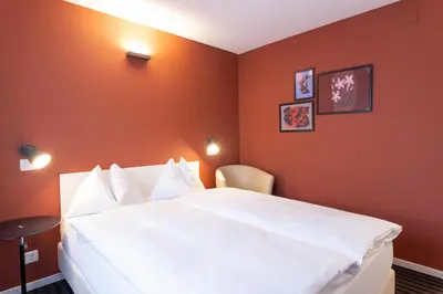a bedroom with a large white bed with orange walls at Self Check-In Hotel David 22 in St. Gallen
