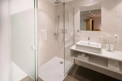 a white bathroom with a sink and a shower at Best Western Hotel Rebstock in Rorschacherberg