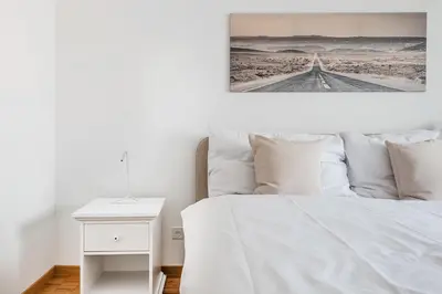 a bedroom with a white bed and a white nightstand at SOHO 9 !Gratis Parken, Free Parking! in Kreuzlingen