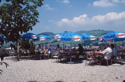 a group of people sitting at tables under umbrellas at Panorama Hotel Freudenberg in Appenzell