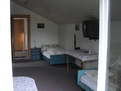 a room with two beds and a tv in it at Panorama Hotel Freudenberg in Appenzell