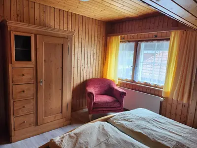 a bedroom with a bed and a chair and a window at Backpacker Bären in Urnäsch