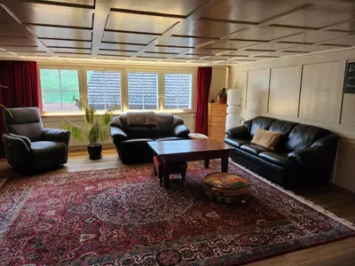 a living room with black leather furniture and a coffee table at Backpacker Bären in Urnäsch
