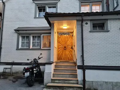 a motorcycle parked in front of a house with a wooden door at Backpacker Bären in Urnäsch