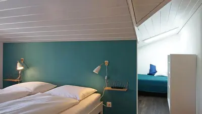 a bedroom with two beds and a blue wall at Alte Metzg - Boutique Pension in Appenzell