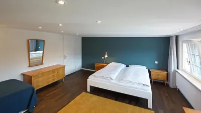 a bedroom with a white bed and a blue wall at Alte Metzg - Boutique Pension in Appenzell