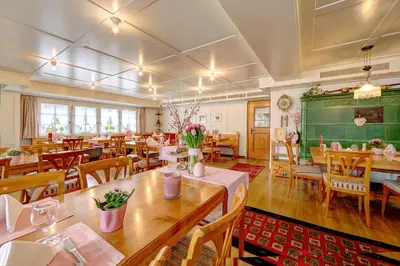 a restaurant with wooden tables and chairs and a greenboard at Hotel Säntis in Appenzell