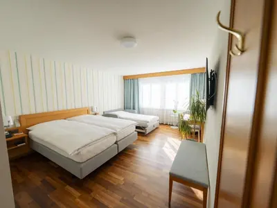 a bedroom with two beds and a chair in it at Hotel Löwen in Appenzell