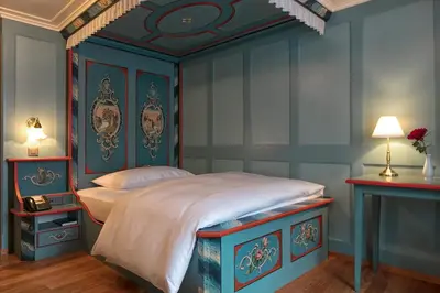 a blue bedroom with a bed with a blue headboard at Hotel Löwen in Appenzell