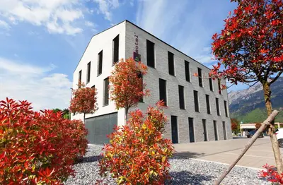 a white building with red flowers in front of it at b-smart motel Sevelen in Sevelen