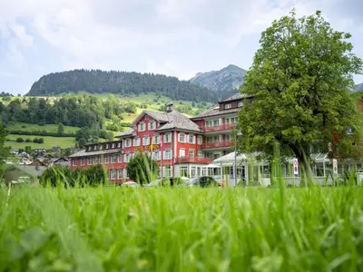 a large red building with a tree in the grass at Hotel Sternen Unterwasser in Unterwasser