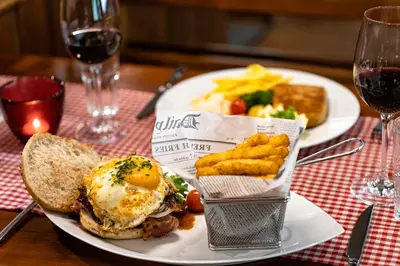 a plate of food with an egg and a sandwich and french fries at Hotel Sternen Unterwasser in Unterwasser