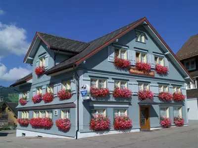 a large blue building with flower boxes on it at Gasthaus Gemsli in Nesslau