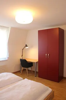 a bedroom with a desk and a red cabinet at Herisau Apartments in Herisau