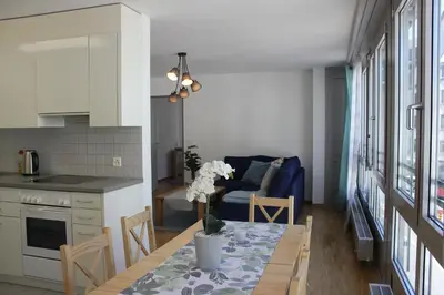 a kitchen and living room with a table and a blue couch at Herisau Apartments in Herisau