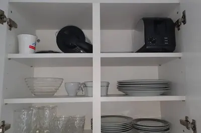 a kitchen shelves with dishes and a microwave at Schönes Studio in Arbon am Bodensee Neu Klimatisiert ! in Arbon
