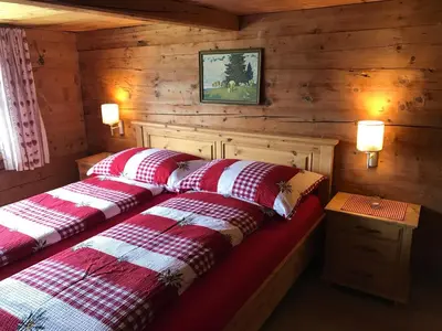 two beds in a room with wooden walls at Alphütte Burst in Alt Sankt Johann