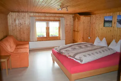 a bedroom with a bed and a chair and a window at BnB-Blomberg in Ebnat